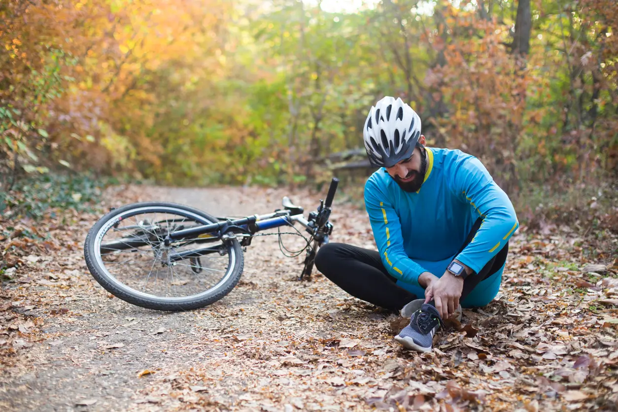 Man fallen off a bike on a leafy road